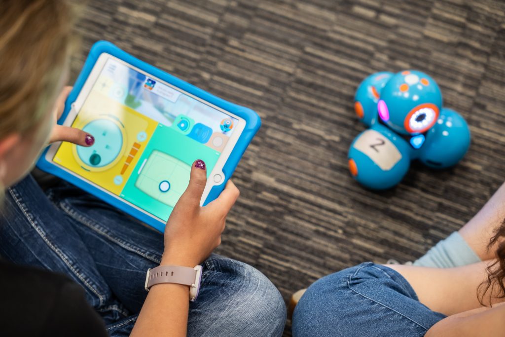 Ein Kind steuert mit einem Tablet einen Roboter